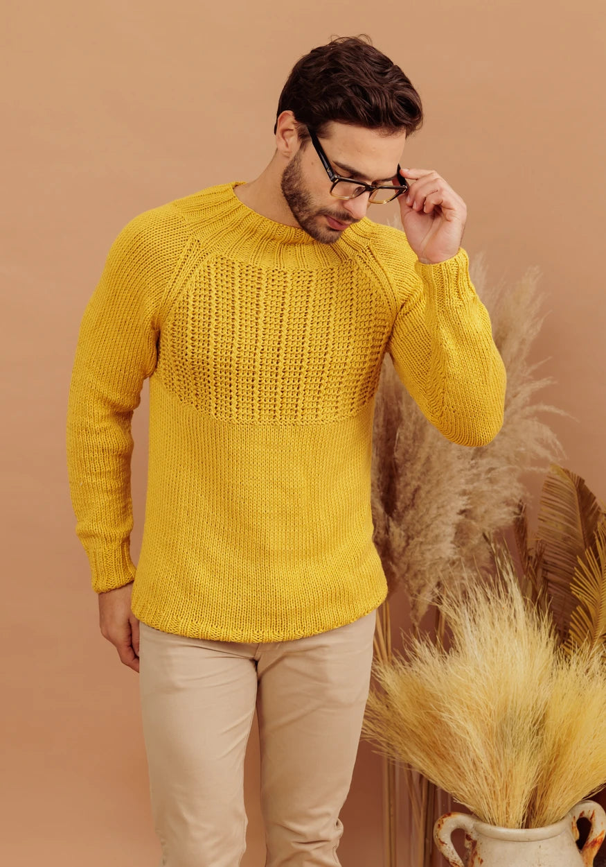 Man wearing a handmade knitted sweater made with Circulo Aloe Vera yarn in mustard yellow. The lightweight sweater features textured stitch details and a comfortable fit, showcasing the yarn's softness, drape and suitability for stylish knitwear.
