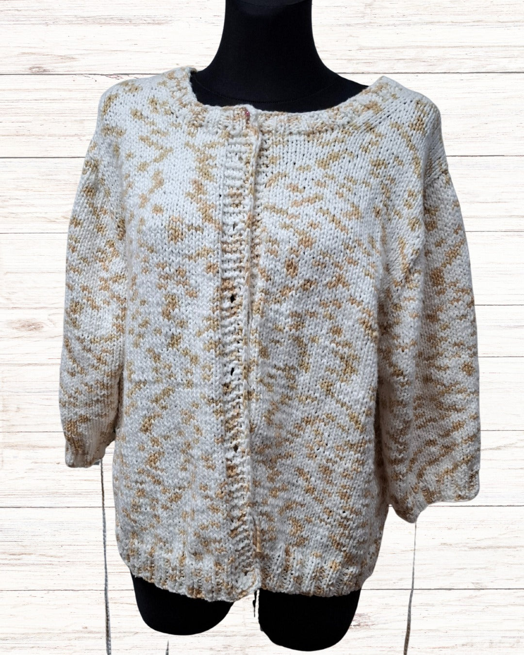 Circulo InLove - 100% Brazilian Cotton Yarn (125m/100g)- A chunky knit cardigan sweater with a beige and white variegated pattern, made by Mealana Austria, displayed on a black mannequin torso against a light wood plank background.