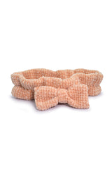 Círculo Amigurumi Pelúcia – Polyester Chenille Yarn (131 m / 85 g) - A peach-colored textured fabric headband with a matching bow, displayed on a clean white background.