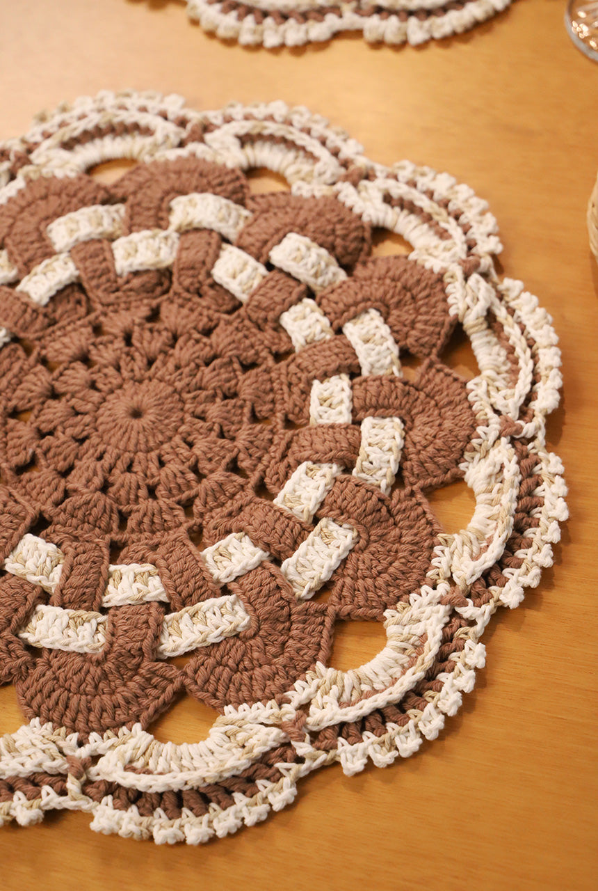 Círculo Natural Cotton Multicolor 4/6 – Cotton Yarn (226 m / 200 g) – A round crocheted doily or placemat in brown and cream, laid flat on a wooden table. The item has an intricate floral and geometric crochet pattern with a scalloped edge.