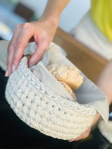 Circulo Barroco Natural Brilho  - Natural Cotton Yarn Gold/Silver, 657m / 433m, 400g - A close-up of a hand holding a cream-colored crocheted basket lined with a light beige fabric, containing two rustic bread rolls.