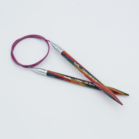 KnitPro Symfonie 2 fixed circular knitting needles with swivel cable, 60 cm - Circular knitting needles with a colorful wood-grain pattern in green, red, and orange, featuring silver metal tips and a purple cable, shown on a light gray background.